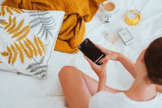 white woman with dark hair holding a smartphone looking at a pregnancy app