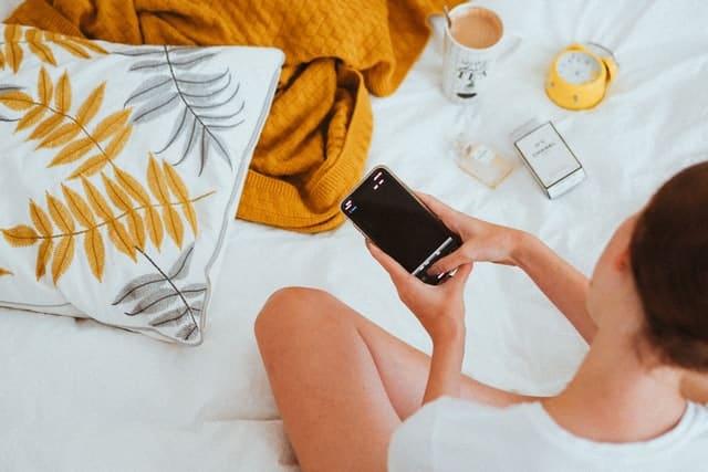 white woman with dark hair holding a smartphone looking at a pregnancy app
