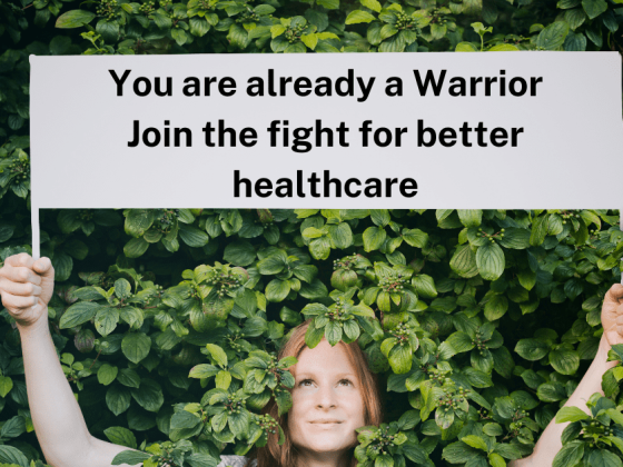 red haired woman deep in green leaves, holding a sign that says you are already a warrior join the fight for better healthcare illustrating the fertility activism article on best fertility now