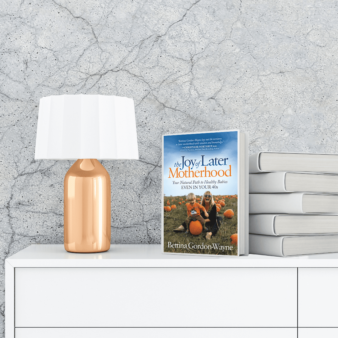 The Joy of Later Motherhood: Your Natural Path to Healthy Babies Even in Your 40’s book on a white chest of draws and a gold lamp to the left with a white lampshade