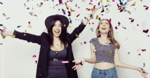 two women celebratying with glitter strands falling from the sky would you do surrogacy for your best friend