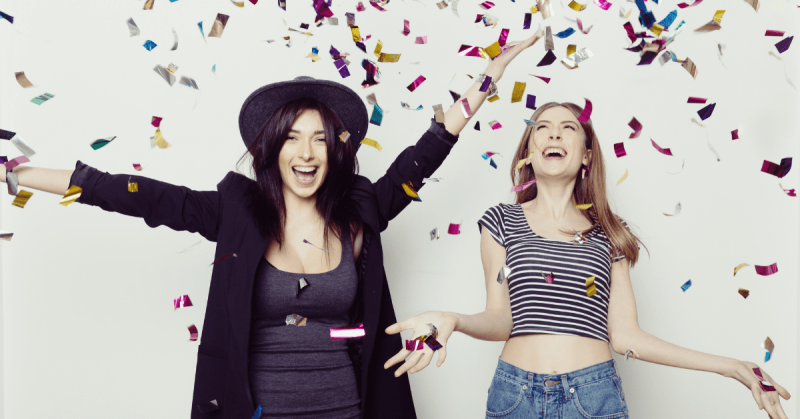 two women celebratying with glitter strands falling from the sky would you do surrogacy for your best friend