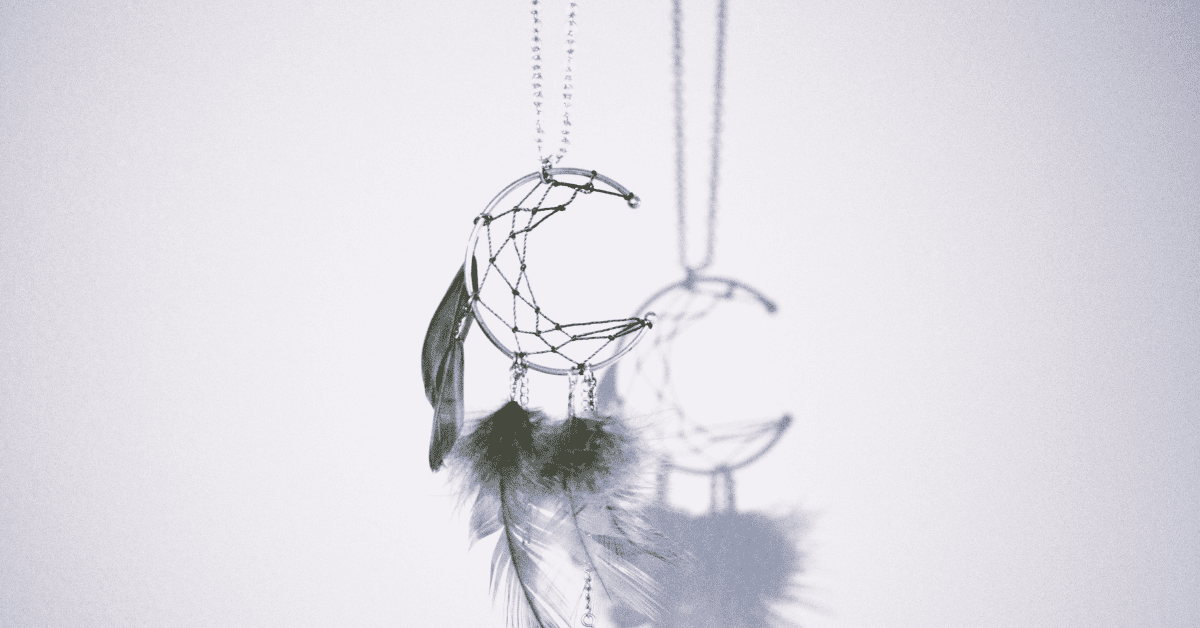 silver moon pregnamcy dreams catcher with feathers on a blue grey background