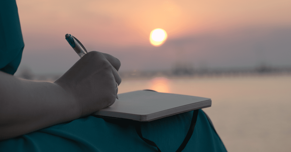 woman in a blue dress writing a letter with the evening sun low in the sky illustrating the article Dear Future Egg Donor Mama