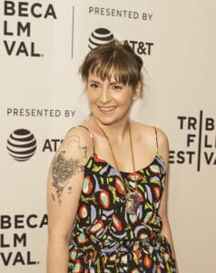 Lena Dunham in a black and multicolour leaves dress, illustrating Celebrities with endometriosis