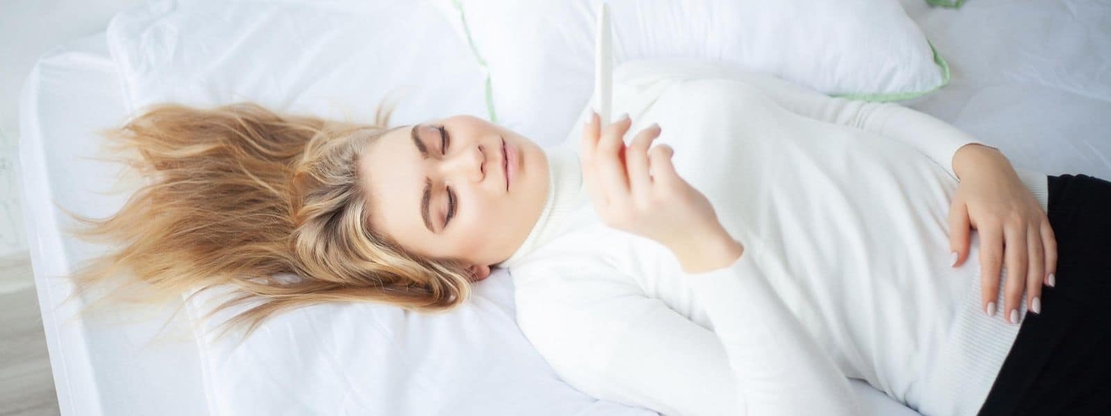 Egg Donation and Surrogacy - lady lying on bed looking at pregnancy test