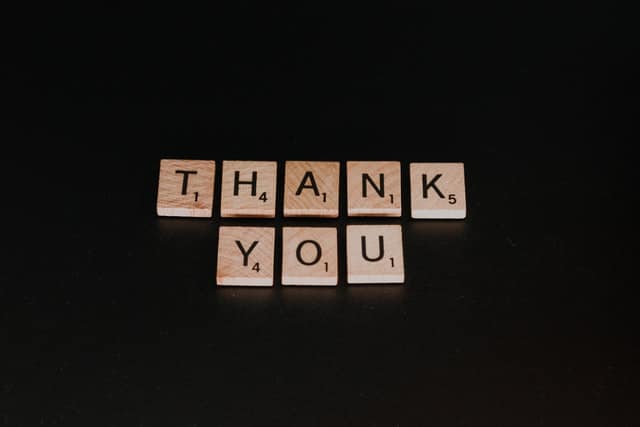 Thank you written in scrabble tiles on a black background
